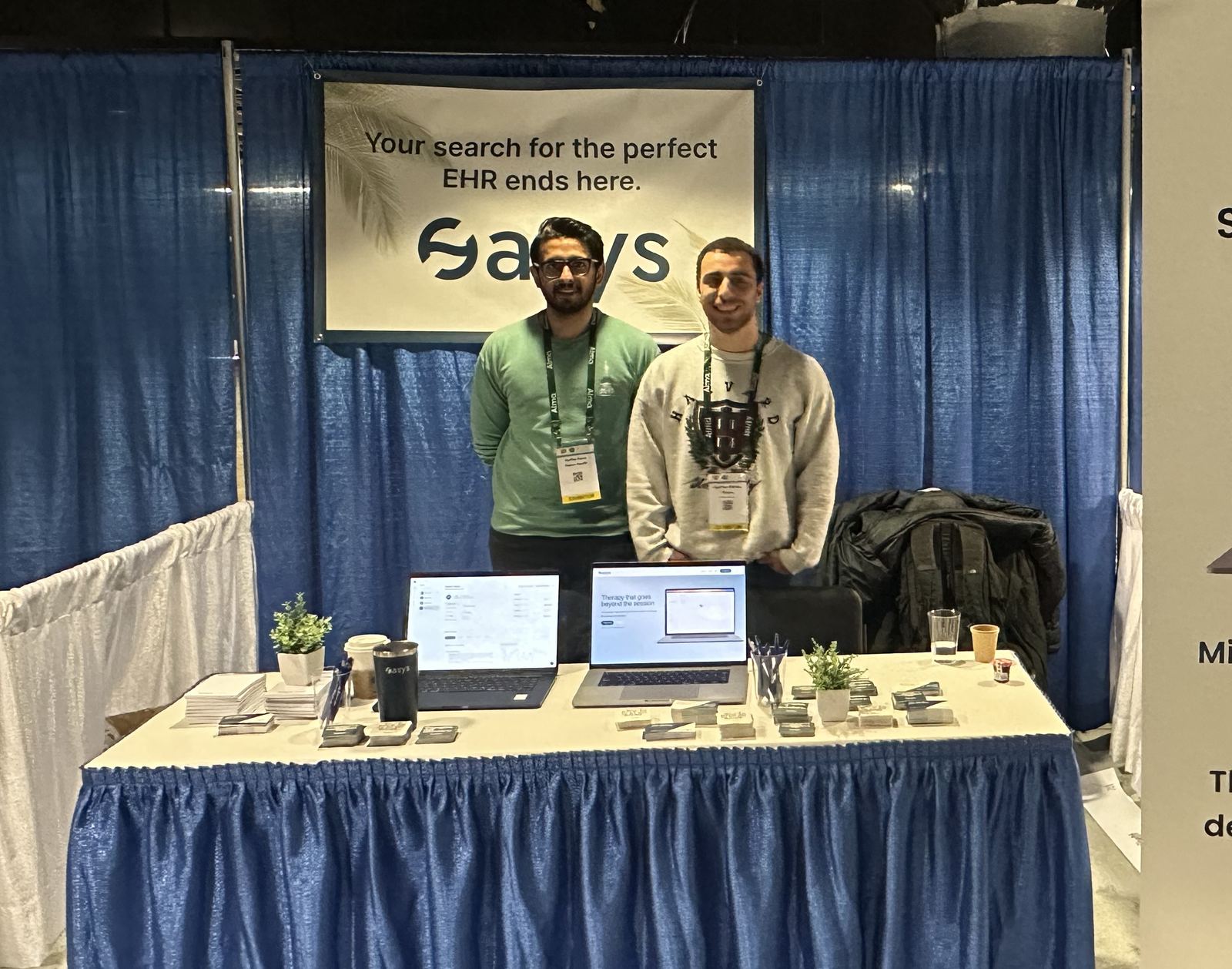 Hashem Abdou and Raffay Rana smiling behind their booth at their first conference.
